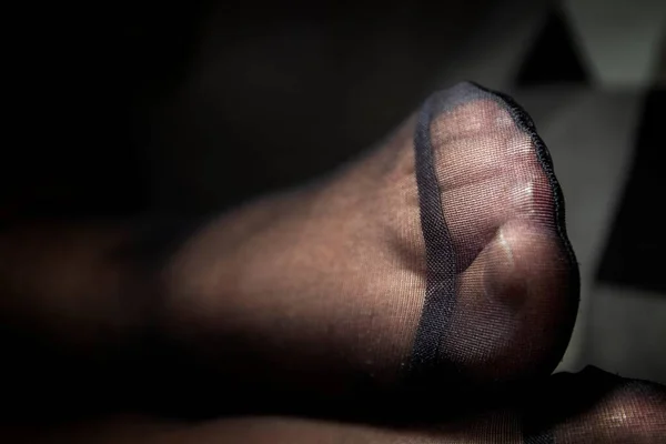 A portrait of a black pantyhose foot zoomed in at the reinforced nylon at the toes.
