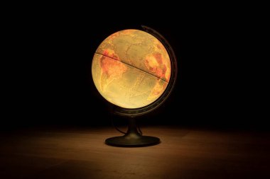 Karanlık bir odadaki ahşap bir zeminde ışık yayan bir kürenin portresi. Dünyayı tasvir eder ve dünyayı keşfetmek için ya da bir komodin olarak mükemmeldir..