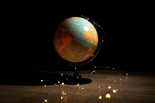 暗い部屋の木製の床の上のライトに囲まれた地球のスタンドの肖像画 それは地球を描き 世界を探索するのに最適です — ストック写真