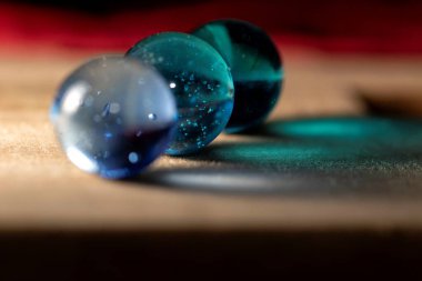 Tahta bir yüzeye renkli yansıyan üç renkli bilyenin yakın plan portresi. Misketler mavinin farklı tonlarıdır..