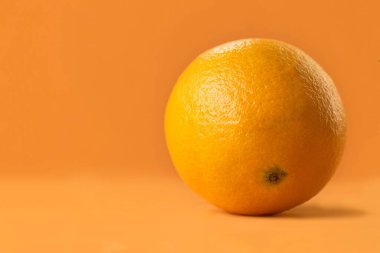 Turuncu arka planda bir portakal portresi. Taze meyve C vitamini ile doludur. Sağlığınız için harikadır ve çok lezzetlidir..