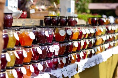 Beervelde / Belçika - 13 Ekim 2019: Bir yığın renkli cam kavanoz reçel sergilenen yerel bir market tezgahının portresi. Reçel kavanozları el yapımı ve taze..