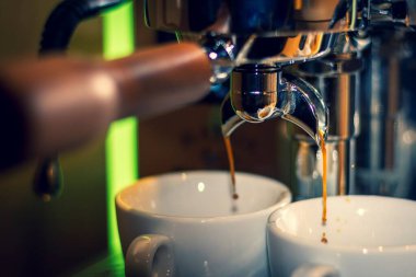 Bir kahve makinesinin hortumunun portresi. Taze yapılmış ve öğütülmüş fasulyeden sıcak kahve yapılıyor..