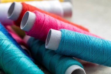 Diğer ipliklerin üzerinde duran üç renkli iplik makarasının portresi. İplik ya da tel bir dikiş projesi ya da başka bir iğne işi için kullanılmaya hazır..