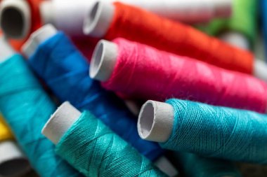 Birden fazla dikiş ipliği rulosunun portresi. İplik makaralarının hepsinin rengi farklı. İplik ya da tel bir çeşit dikiş için kullanılmaya hazır..