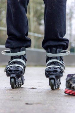 İç patenlerin üzerinde duran birinin bacaklarının portresi. Beton oval pistte patenlerle korunmasız yarışmaya hazır..