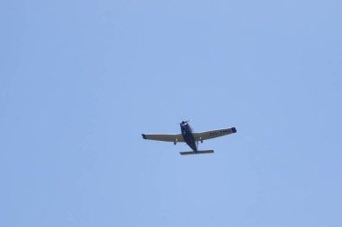 A portrait of a sport airplane flying through a blue sky. The small plane, aircraft is flying straight through the air with its wings level to the ground.