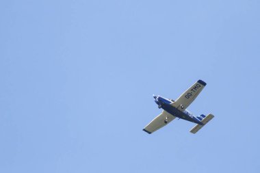 A portrait of a sport plane flying through a blue sky. The small airplane, aircraft is flying straight through the air with its wings level to the ground.