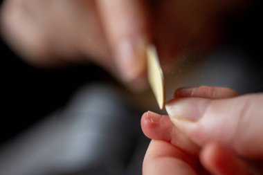 Küçük bir bebek elinin tırnaklarını kestikten sonra törpüleyen bir annenin yakın plan portresi. Çocukların tırnakları küçük bir dosyayla dolduruluyor çünkü kesmekten hala keskinler..