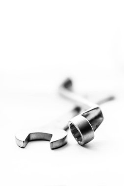 Açık uçlu bir ingiliz anahtarının siyah beyaz bir portresi ve birbirinin üstünde duran kutu ucu anahtarı. Metal aletler beyaz arka planda duruyor..