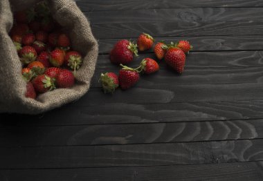 Koyu ahşap arka planda bir çantada çilek