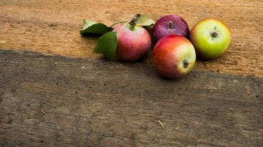 Tahta masada yeşil yapraklı taze kırmızı elmalar. Ahşap arka planda. Metin için boş alan. Üst görünüm