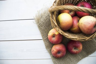 Ahşap arka planda elma dolu bir sepet.