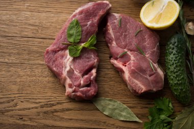 Çiğ sulu biftekler ahşap bir arka planda kızartılmaya hazır.