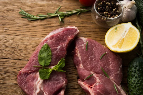 Çiğ sulu biftekler ahşap bir arka planda kızartılmaya hazır.