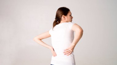 Attractive teenage girl suffers from backache. All on white background clipart