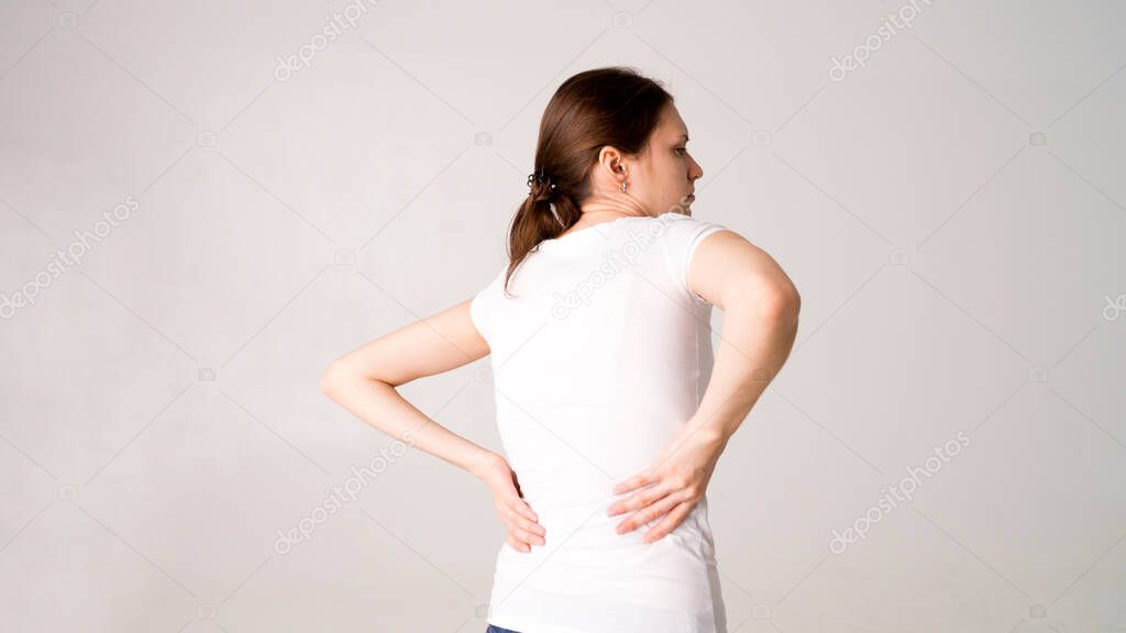Attractive teenage girl suffers from backache. All on white background