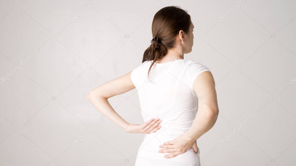 Attractive teenage girl suffers from backache. All on white background
