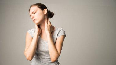 Yorgun kadın boyun ağrısı çekiyor, gergin kaslara masaj yapıyor.