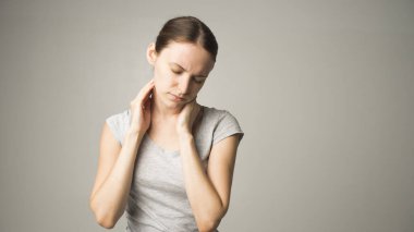 Yorgun kadın boyun ağrısı çekiyor, gergin kaslara masaj yapıyor.