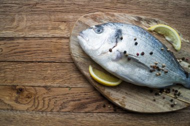 Çiğ balık pişirme ve malzemeler. Dorado, limon, otlar ve baharatlar. Taş masadaki üst görünüm