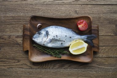 Çiğ balık pişirme ve malzemeler. Dorado, limon, otlar ve baharatlar. Taş masadaki üst görünüm