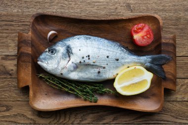 Çiğ balık pişirme ve malzemeler. Dorado, limon, otlar ve baharatlar. Taş masadaki üst görünüm