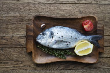 Çiğ balık pişirme ve malzemeler. Dorado, limon, otlar ve baharatlar. Taş masadaki üst görünüm