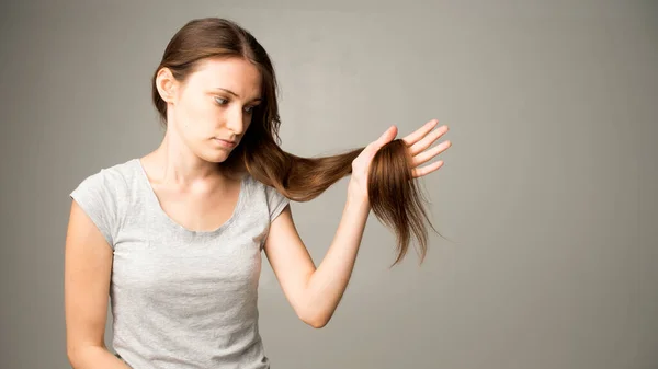 Girl Gray Background Holds Hair Her Hand — Stock Photo, Image