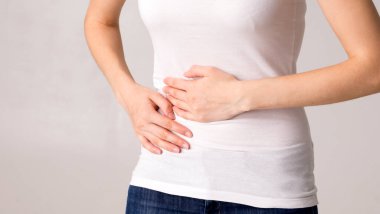 Genç ve güzel bir kadın karnını tutuyor. Karın ağrısı.