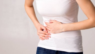 Genç ve güzel bir kadın karnını tutuyor. Karın ağrısı.