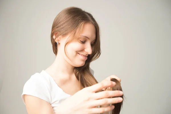 Meisje Een Grijze Achtergrond Houdt Een Haar Haar Hand — Stockfoto