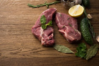 Çiğ sulu biftekler ahşap bir arka planda kızartılmaya hazır.