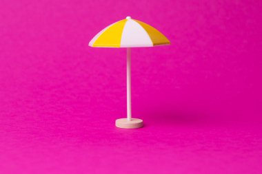 Pembe arka planda çok renkli plaj şemsiyesi