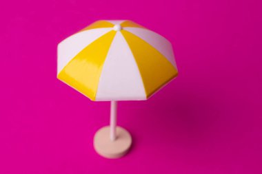 Pembe arka planda çok renkli plaj şemsiyesi
