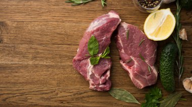 Çiğ sulu biftekler ahşap bir arka planda kızartılmaya hazır.