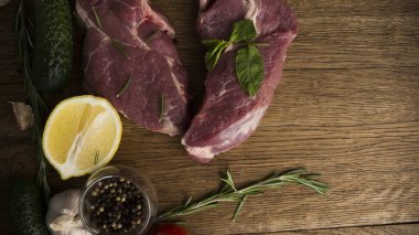 Çiğ sulu biftekler ahşap bir arka planda kızartılmaya hazır.