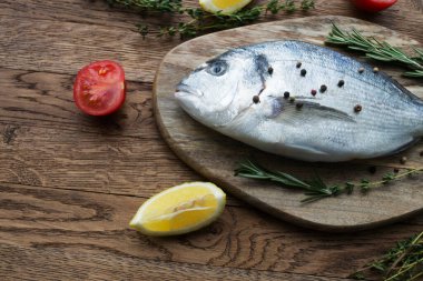 Çiğ balık pişirme ve malzemeler. Dorado, limon, otlar ve baharatlar. Taş masadaki üst görünüm