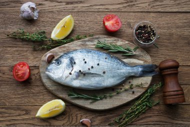 Çiğ balık pişirme ve malzemeler. Dorado, limon, otlar ve baharatlar. Taş masadaki üst görünüm