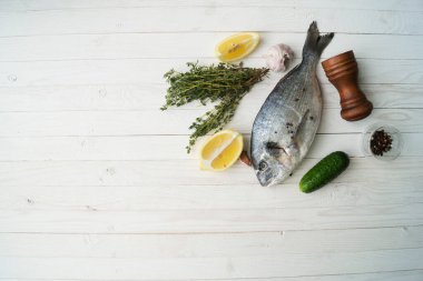 Çiğ balık pişirme ve malzemeler. Dorado, limon, otlar ve baharatlar. Taş masadaki üst görünüm