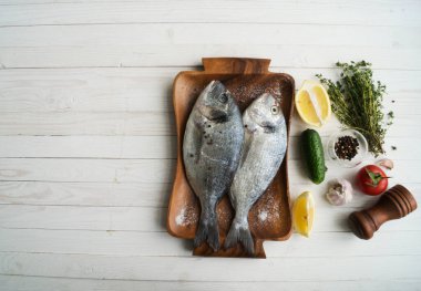 Deniz ürünleri. Tahtada limon, biber, baharat ve biberiye ile marine edilmiş iki çiğ gökkuşağı alabalığı. Sağlıklı gıda ve diyet konsepti.