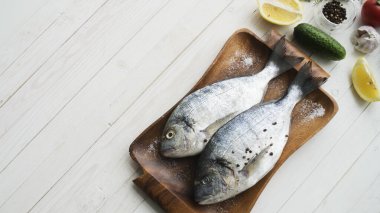 Deniz ürünleri. Tahtada limon, biber, baharat ve biberiye ile marine edilmiş iki çiğ gökkuşağı alabalığı. Sağlıklı gıda ve diyet konsepti.