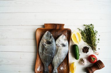 Deniz ürünleri. Tahtada limon, biber, baharat ve biberiye ile marine edilmiş iki çiğ gökkuşağı alabalığı. Sağlıklı gıda ve diyet konsepti.