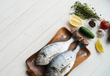 Deniz ürünleri. Tahtada limon, biber, baharat ve biberiye ile marine edilmiş iki çiğ gökkuşağı alabalığı. Sağlıklı gıda ve diyet konsepti.