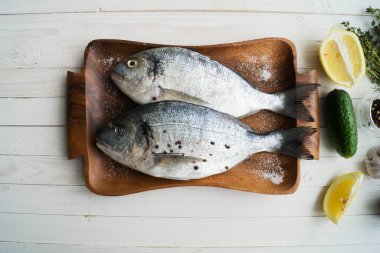 Deniz ürünleri. Tahtada limon, biber, baharat ve biberiye ile marine edilmiş iki çiğ gökkuşağı alabalığı. Sağlıklı gıda ve diyet konsepti.