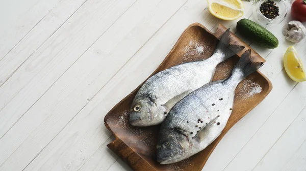 Deniz ürünleri. Tahtada limon, biber, baharat ve biberiye ile marine edilmiş iki çiğ gökkuşağı alabalığı. Sağlıklı gıda ve diyet konsepti.