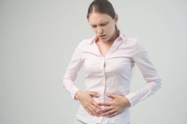 Genç ve güzel bir kadın karnını tutuyor. Karın ağrısı.