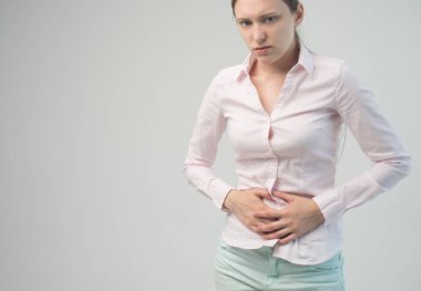 Genç ve güzel bir kadın karnını tutuyor. Karın ağrısı.