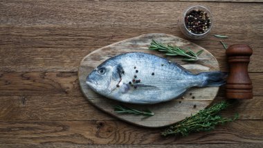 Çiğ balık pişirme ve malzemeler. Dorado, limon, otlar ve baharatlar. Taş masadaki üst görünüm