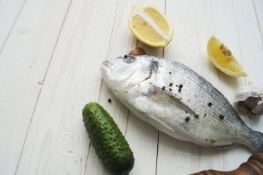 Çiğ balık pişirme ve malzemeler. Dorado, limon, otlar ve baharatlar. Taş masadaki üst görünüm